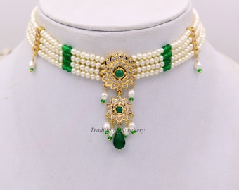 Puede incluir: Un collar gargantilla de oro con un diseño de perlas multi-hilo y detalles verdes. El collar presenta un colgante con un diseño floral y piedras verdes.