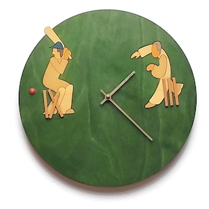 May include: A round, green wooden wall clock with a cricket theme. The clock features stylized wooden figures of a batsman and a fielder. The clock hands are gold-colored, and a small red ball is also present.