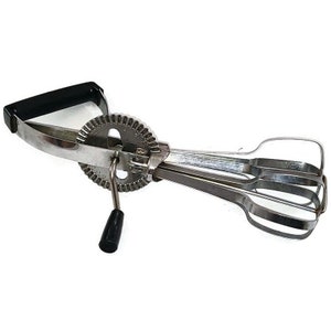 May include: A silver hand-crank egg beater with a black handle and a gear-like mechanism. The beater has three metal whisks.