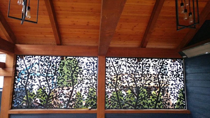 May include: Two black metal panels with a leaf design, installed on a wooden ceiling. The panels are translucent and allow light to pass through.