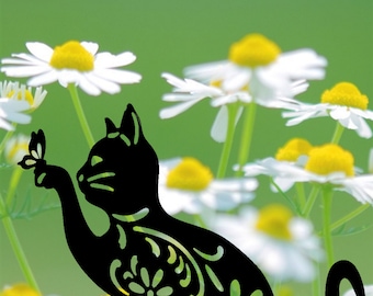 May include: Black silhouette of a cat with a floral design, sitting in a field of white daisies with yellow centers.