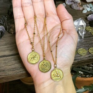 May include: Three gold necklaces with zodiac signs pendants. The pendants feature a bull, a goat, and a fish.