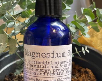 Peut inclure: Une bouteille en verre bleu avec un vaporisateur noir, étiquetée "Magnesium Spray". L'étiquette indique que le magnésium est un minéral essentiel qui peut aider à soulager les douleurs musculaires et articulaires, stimuler l'énergie, favoriser la relaxation et le sommeil réparateur. Les ingrédients sont indiqués comme étant du chlorure de magnésium et de l'eau distillée dans un rapport de 1:1. La bouteille est posée sur une surface brune.