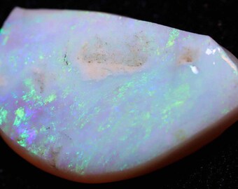 May include: A white opal gemstone with green and purple iridescence. The opal is a half-moon shape and has a smooth, polished surface.