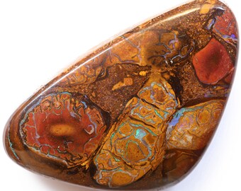 Puede incluir: Una piedra preciosa de ópalo marrón, roja y azul con una forma rugosa y natural. El ópalo presenta una variedad de colores y patrones, incluyendo rojo, naranja, amarillo, verde, azul y morado.