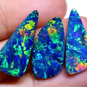 May include: Three iridescent black opal gemstones with a triangular shape. The opals have a blue, green, and orange color.
