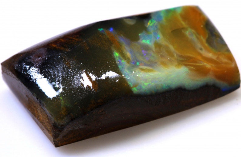 May include: A black opal gemstone with a dark brown matrix. The opal has a green, blue, and yellow iridescent sheen.