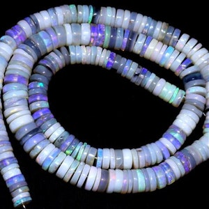 May include: A strand of iridescent opal beads in shades of white, blue, and purple. The beads are round and flat, and they are strung on a clear thread. The beads are approximately 6mm in diameter.