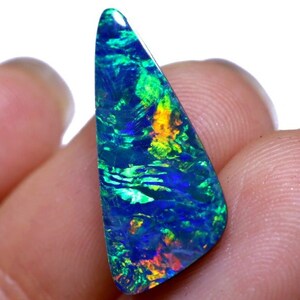 May include: A triangular, iridescent opal gemstone with a blue, green, and orange play of color. The opal is set in a silver bezel and has a polished finish.