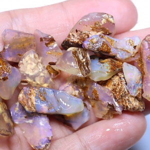 May include: A collection of small, rough, iridescent opal stones with a mix of white, purple, and brown colors.