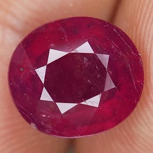 Può includere: Una pietra preziosa di rubino di forma ovale di colore rosso intenso con un motivo a forma di stella all'interno.