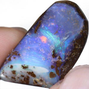 Könnte beinhalten: Ein polierter Opal-Edelstein mit einem lebendigen Farbspiel. Der Stein zeigt eine Mischung aus Blau, Grün und Orange mit einer dunkelbraunen Matrix. Die Oberfläche des Opals ist glatt und reflektierend und zeigt seine innere Irisierung.