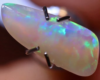 May include: A white opal gemstone with green and blue iridescence. The opal is held in place by metal prongs.
