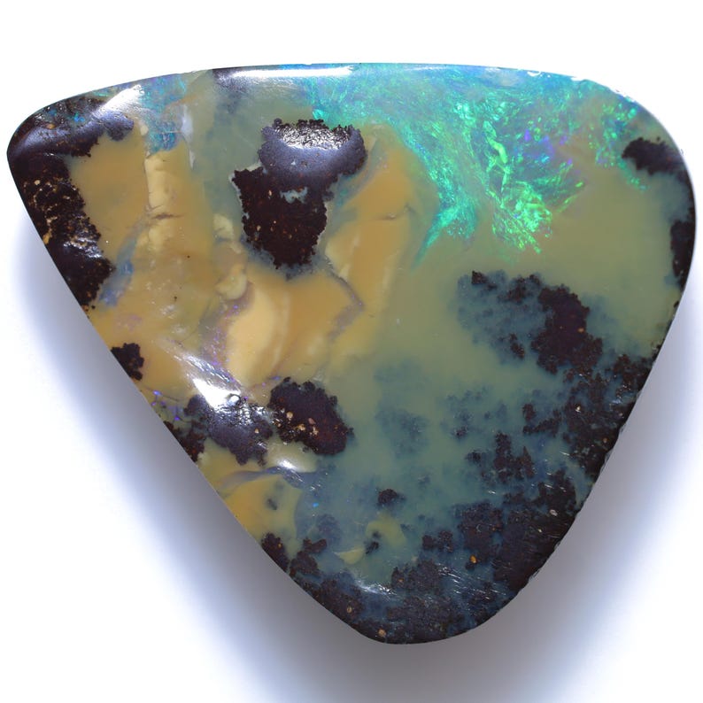 Puede incluir: Una piedra preciosa de &oacute;palo pulido con forma triangular. La piedra presenta una mezcla de colores, incluyendo amarillo, azul, verde y marr&oacute;n oscuro. El &oacute;palo tiene un patr&oacute;n y textura &uacute;nicos, con &aacute;reas de iridiscencia.
