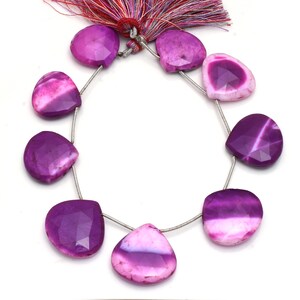 May include: A strand of heart-shaped, faceted gemstones in shades of purple and pink. The beads are strung on a silver wire and are arranged in a circular pattern. A tassel with purple and red threads is visible at the top.