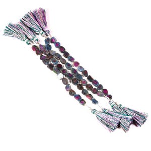 May include: Strands of gemstone beads with a mix of blue, purple, and gray tones. Each strand is finished with a tassel of green, purple, and white threads. The beads have an irregular, organic shape.