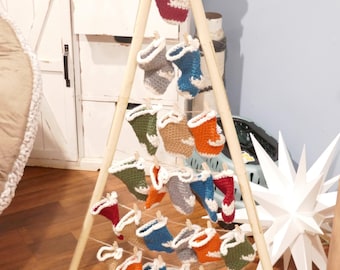 May include: A wooden A-frame display holding multiple miniature crocheted stockings in various colors, including red, blue, green, and orange. Each stocking has a white cuff and is suspended by a string, creating a festive, handmade aesthetic.