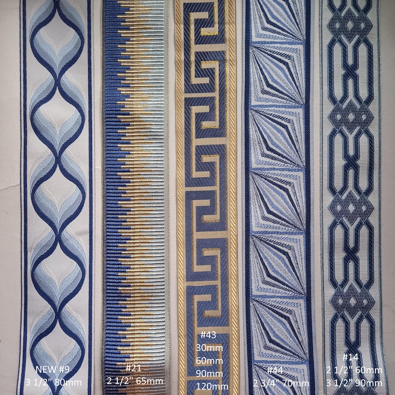 May include: A collection of decorative ribbons in various blue and gold patterns. Designs include geometric shapes, Greek key, and stylized floral motifs. Widths range from 2 1/2 inches to 3 1/2 inches. The image includes text labels with product numbers and measurements.