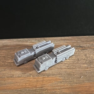 May include: Two gray toy fire trucks with ladders on top. The trucks have black wheels and are made of plastic.