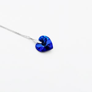 May include: A silver chain necklace with a blue heart-shaped pendant.