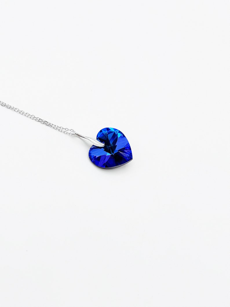 May include: A silver chain necklace with a blue heart-shaped pendant.