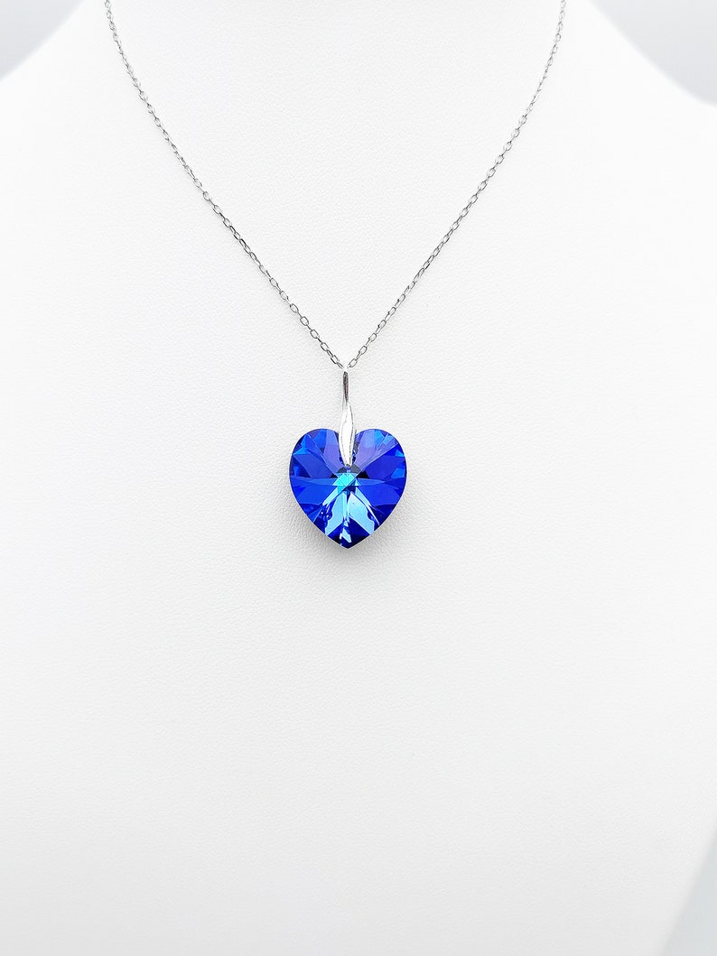 May include: A silver chain necklace with a blue crystal heart pendant.