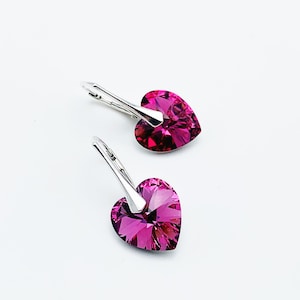Può includere: Un paio di orecchini a forma di cuore in argento con accenti di cristallo rosa.