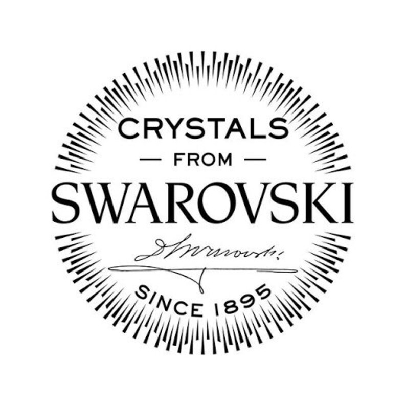 Puede incluir: Logotipo en blanco y negro para cristales Swarovski. El logotipo presenta un c&iacute;rculo con l&iacute;neas radiantes, el texto "Crystals from Swarovski" y la firma "Swarovski" con el texto "Since 1895" debajo.