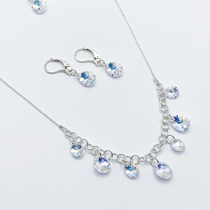 Puede incluir: Un collar de plata con una cadena delicada y gotas de cristal colgantes. Se incluyen pendientes de cristal a juego con ganchos de plata.