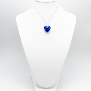 May include: A silver chain necklace with a blue crystal heart pendant.