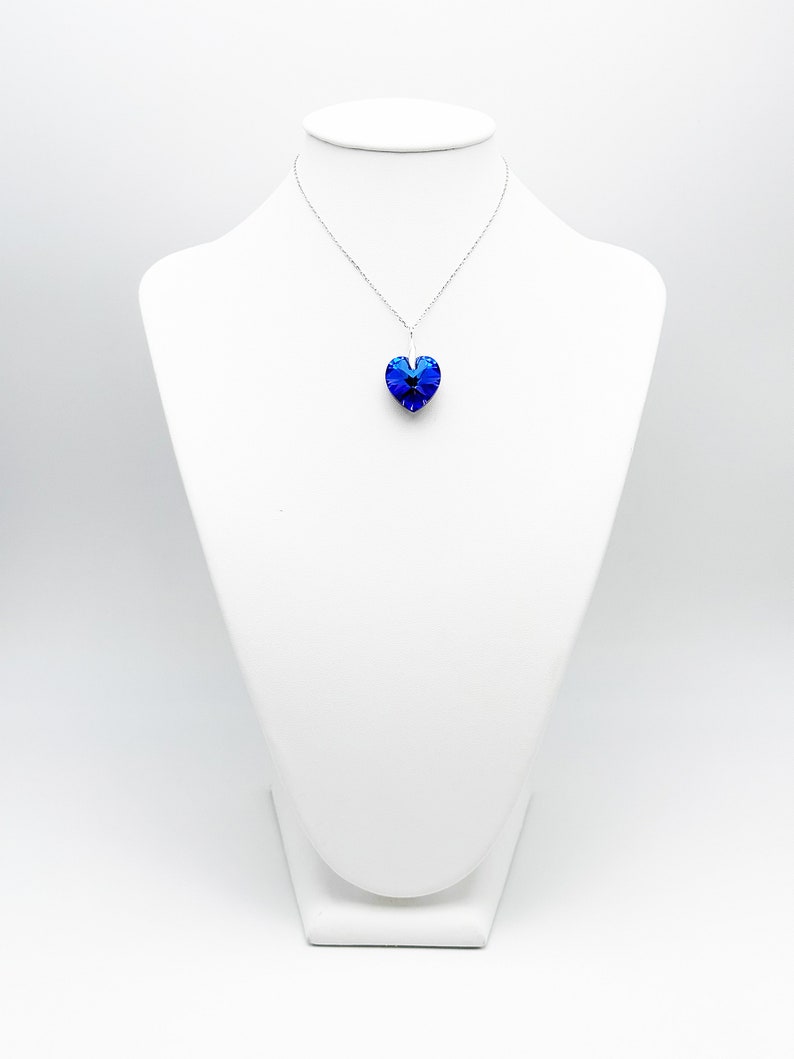 May include: A silver chain necklace with a blue crystal heart pendant.