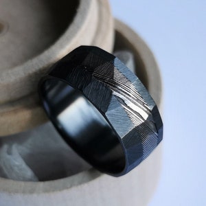 Black zirconium and stainless damascus steel band with rough facets. Handmade and customizable.