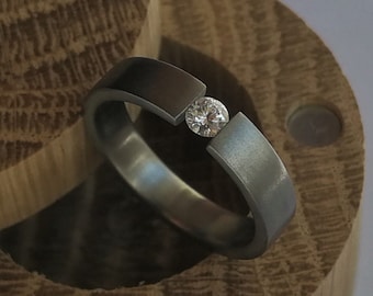 Titanium tension ring with round brilliant cut stone setting. Brushed finish. Handmade and customizable.