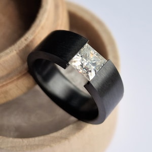 Black zirconium tension band with princess cut gemstone setting. Handmade and customizable.