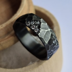 Faceted black zirconium band with flush set moissanites. Handmade and customizable.