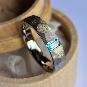 Faceted titanium tension ring with baguette cut stone setting.
