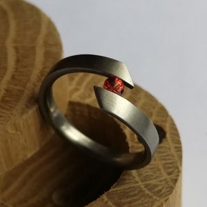 Anillo de tensión de titanio con engaste de gema redonda de talla brillante. Acabado cepillado. Hecho a mano y personalizable.