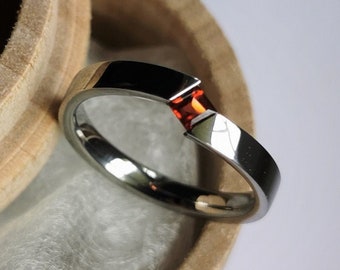 Unique handmade polished titanium tension ring with princess cut stone setting.