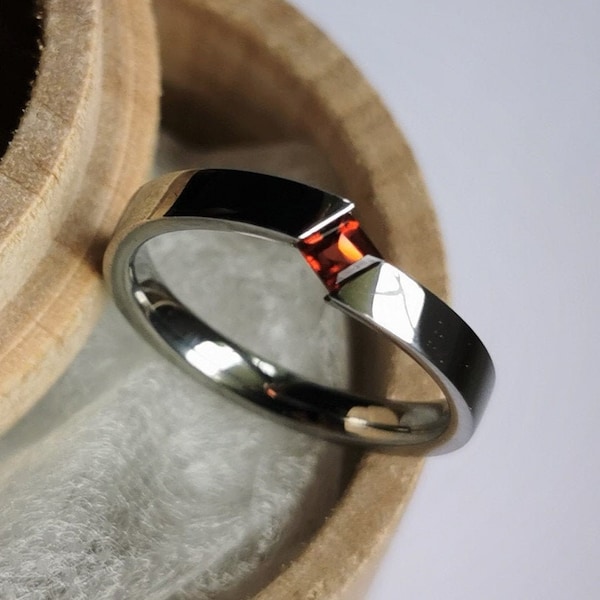 Unique handmade polished titanium tension ring with princess cut stone setting.