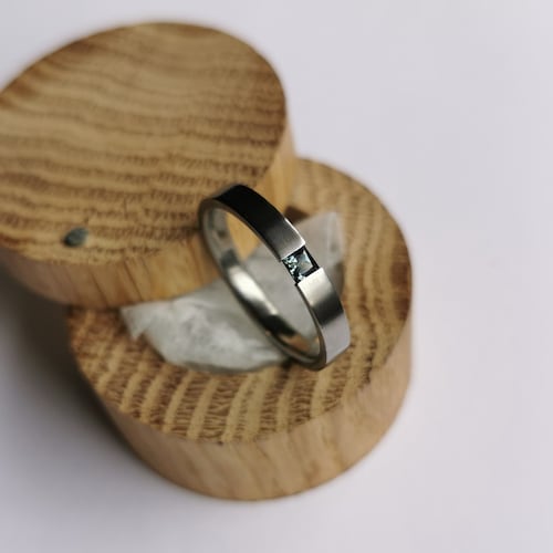 Bague de tension en titane avec sertissage de pierres précieuses de taille princesse. Finition brossée. Fait main et personnalisable.