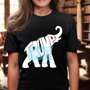 Puede incluir: Camiseta negra con una silueta de elefante blanca. El elefante está formado por las palabras "TRUMP" y "SRUBY DOOYLE LANE".
