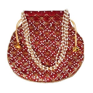 May include: A deep red drawstring pouch featuring a repeating gold embroidered star pattern and white pearl bead embellishments. The bag includes a multi-strand white pearl handle and gold-toned metal drawstring ends, creating a textured surface.