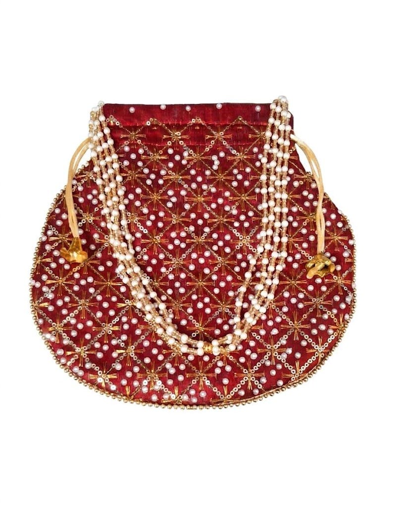 May include: A deep red drawstring pouch featuring a repeating gold embroidered star pattern and white pearl bead embellishments. The bag includes a multi-strand white pearl handle and gold-toned metal drawstring ends, creating a textured surface.