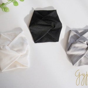 May include: Three fabric headbands in white, black, and gray. Each headband is folded and tied in a knot at the center.
