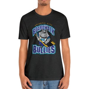 May include: A dark heather grey t-shirt with a graphic of a cartoon bulldog holding a hockey stick. The text "Atlantic City Boardwalk Bullies" is printed on the shirt.