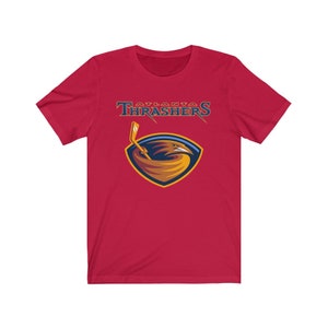 May include: Red short-sleeved t-shirt with the Atlanta Thrashers logo. The logo features a gold and blue hawk with a hockey stick.