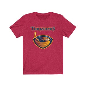 May include: Red t-shirt with a graphic of the Atlanta Thrashers NHL team logo. The logo features a gold and blue hawk with a hockey stick.