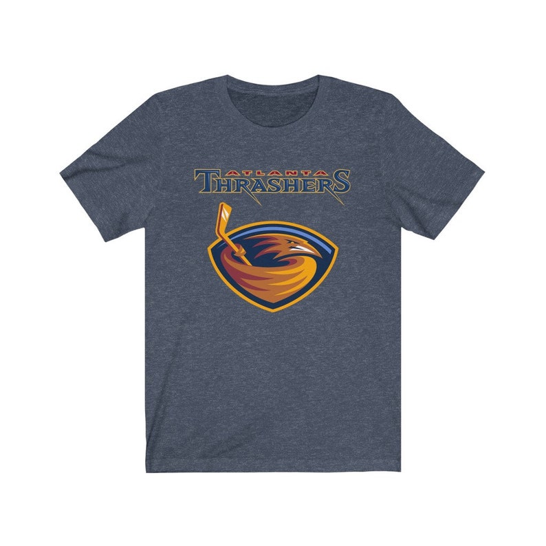 May include: A heather blue t-shirt with the Atlanta Thrashers logo. The logo features a red, orange, and yellow bird with a hockey stick in its beak. The text "Atlanta Thrashers" is above the bird.