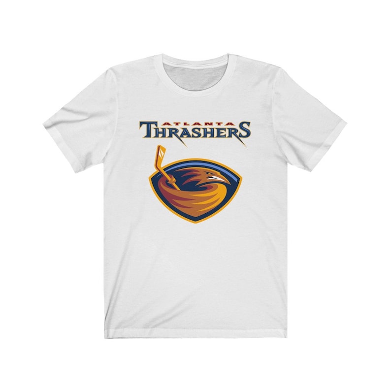 May include: White t-shirt with a navy blue and orange Atlanta Thrashers logo. The logo features a hawk with a hockey stick.