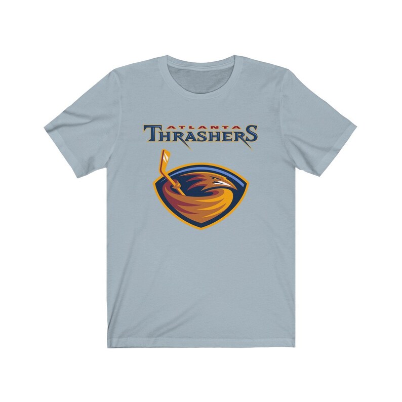 May include: A light blue t-shirt with the Atlanta Thrashers logo. The logo features a red, white, and blue color scheme with a stylized bird holding a hockey stick.